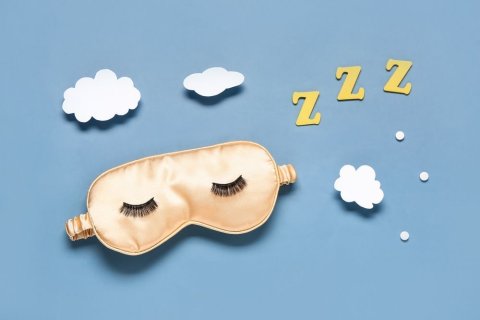 Diese Collage zeigt vor hellblauem Hintergrund eine goldene Schlafmaske mit aufgeklebten schwarzen Wimpern, weiße Wölkchen und dreimal den Buchstaben Z sowie drei weiße Punkte. 