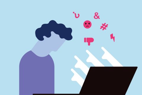 Flache Illustration auf hellblauem Grund. Links sitzt eine Person mit dunkelblauem Lockenkopf und lila Oberteil vor einem schwarzen Laptop und senkt den Kopf tief nach vorn. Das Gesicht hat keine Z&uuml;ge. Aus dem Bildschirm steigen wei&szlig;e, kantige Sprechblasen schr&auml;g nach oben. Dar&uuml;ber schweben pinke Symbole: ein rundes Emoji mit zusammengezogenen Brauen und herabgezogenem Mund, ein Daumen nach unten, ein Blitz sowie die Zeichen & und #.