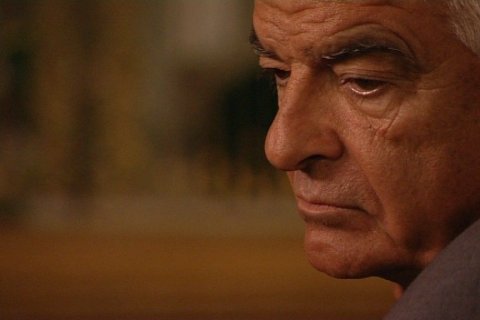 Das Bild zeigt ein verschwommenes Gesicht auf der rechten Seite, während der Rest des Hintergrunds unscharf ist. Der Hintergrund scheint eine Inneneinrichtung mit undeutlichen Formen und Farben zu sein, die möglicherweise auf Objekte oder Dekorationen hinweisen, aber es sind keine spezifischen Details zu erkennen.