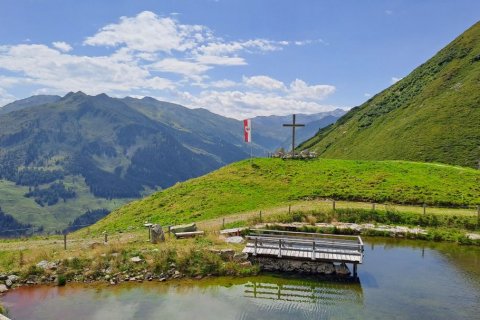 Bergsee mit Gipfelkreuz in den Alpen